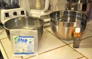 Two large stainless steel mixing bowls with a packet of One Step cleaner and a small bottle of sanitizer
