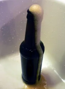 Foam erupting from the neck of a dark bottle