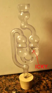 An S-shaped airlock in a rubber stopper, with residue inside marked "icky"